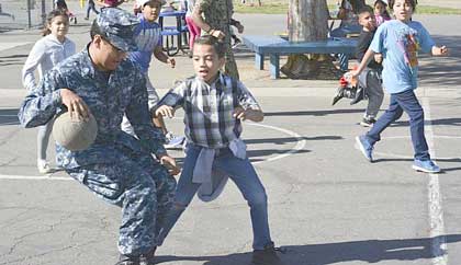 COMMERCE, Calif. (Nov. 13, 2018) Yeoman 2nd Class Arturo Magallanes, assigned to Navy Operational Support Center (NOSC) Los Angeles, plays basketball with students on the playground at Rosewood Park School as part of the NOSC Los Angeles Adopt-a-School program. NOSC Los Angeles provides Reserve Sailors with administrative services and training opportunities while preparing them for strategic deployment to the fleet. U.S. Navy photo by MC2 Pyoung K. Yi.